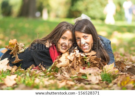 Two Young Friends Laying in the Autumn Park
