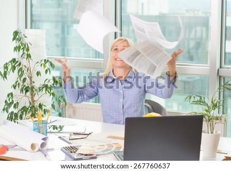 Happy business woman throwing papers in the air at office
