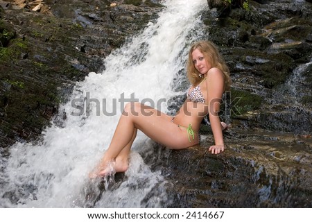 Girl in bikini on rocks w/legs crossed and feet in water cascade at Mingo Falls, Cherokee, NC.