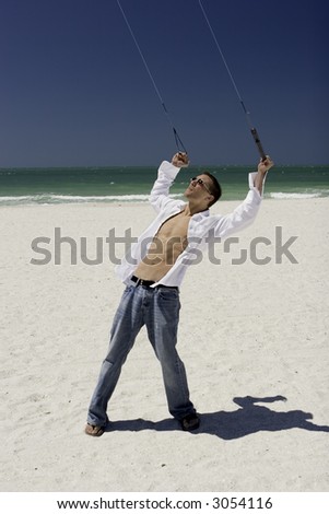 A young man working the control lines of a stunt kite on the public beach in Treasure Island, Florida.