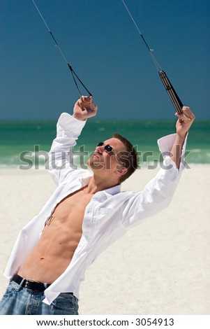 A young man working the control lines of a stunt kite on the beach in Treasure Island, Florida.