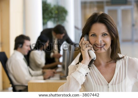 Business women on phone with working team behind
