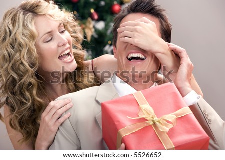 stock photo : Beautiful wife surprising her husband with a gift for christmas