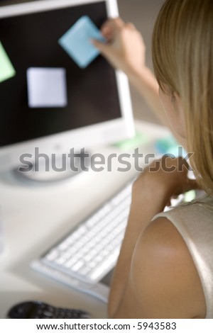 A young woman pasting post-its on her computer