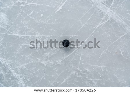 black hockey puck on ice rink.