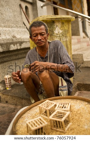 LAMPHUN THAILAND - APRIL 12: Unidentified man sells birds in cages to tourist to let free during Songkran Festival holidays on April 12, 2010 at Wat Phra That Hariphunchai Temple in Lamphun Thailand