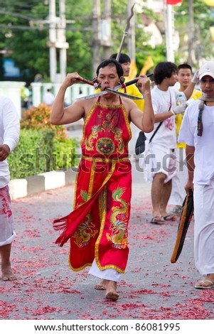 PHUKET, THAILAND - OCTOBER 2: An unidentified devotee of a Chinese shrine gets swords pierced on his cheeks to take part in the 2011 Vegetarian Festival on October 2, 2011 in Phuket, Thailand
