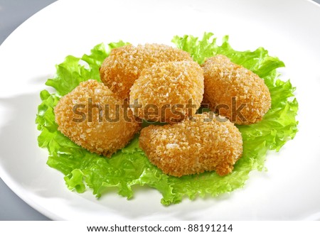 Fried chicken pieces coated with breadcrumbs with lettuce on the white plate