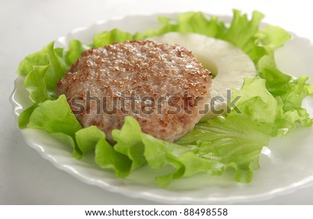 Meat rissole with lettuce and pineapple on the plate
