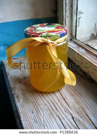 Jar of sweet yellow pure honey with bow on an old retro window sill