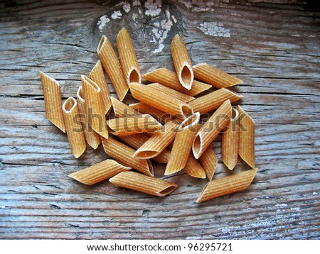 Uncooked brown pasta selection on a wooden rustic background, international food concept, old retro vintage style