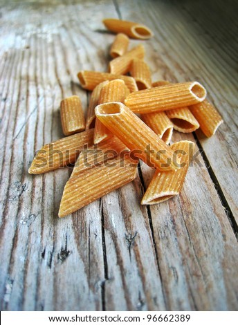 Uncooked brown pasta selection on a wooden rustic background, international food concept, old retro vintage style