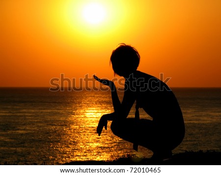 Silhouette of the girl against the sea and the coming sun