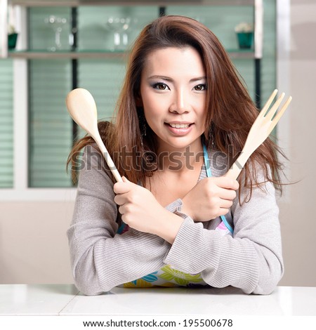 Happy asian woman cooking in the kitchen