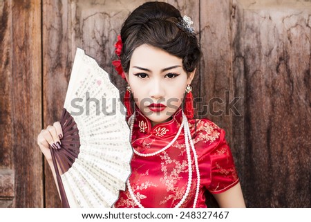 China Girl,Chinese woman red dress traditional cheongsam ,close up portrait with old wood door