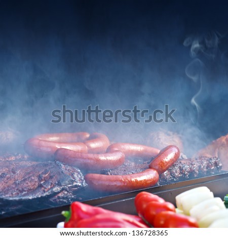Spareribs and garlic sausage on Barbeque Smoker Grill / black copyspace top