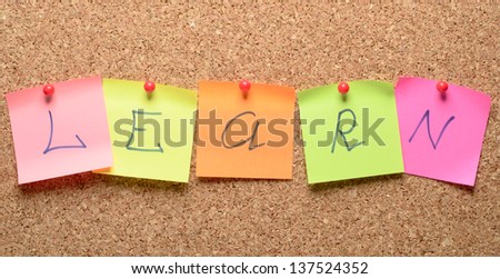 The word learn with stickers note pinned on a cork bulletin board