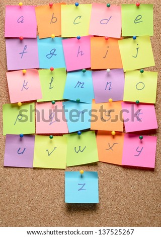 The alphabet with stickers note pinned on a cork bulletin board