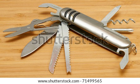Swiss knife with all open blades on a wooden surface