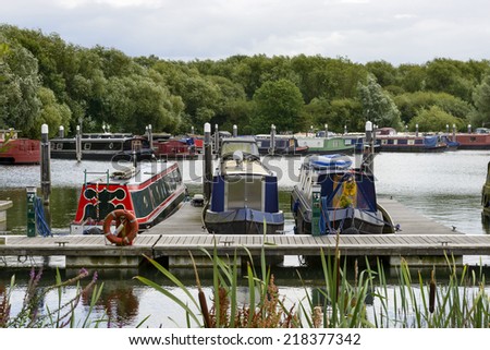 narrow boats at quay in Thames and Kennet Marina, Reading, view of quay at river harbor for narrow boats on river Thames, shot from a point that permits to see how narrow they are