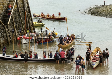 CLOVELLY, UNITED KINGDOM - AUGUST 16  rowing boats teams descend from boat on sand at harbor during Copilot Gigs Regatta rowing competition, shot on 2014 august 16, Clovelly, Devon, United Kingdom