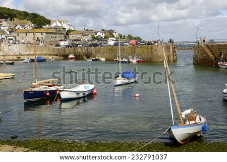 MUSEHOLE, UNITED KINGDOM - AUGUST 18 boats go aground at low tide while people bath in harbor of historic village of Cornwall , shot on 2014 august 18, Musehole, Cornwall, United Kingdom