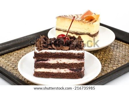 Image of chocolate cake in white dish with White chocolate cake on bamboo woven tray
