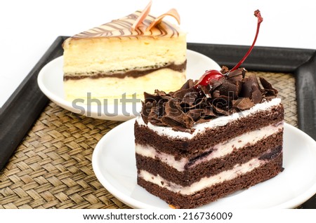 Image of chocolate cake in white dish with White chocolate cake on bamboo woven tray