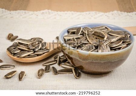 Image of sunflower seeds in ceramic bowl on white fabric