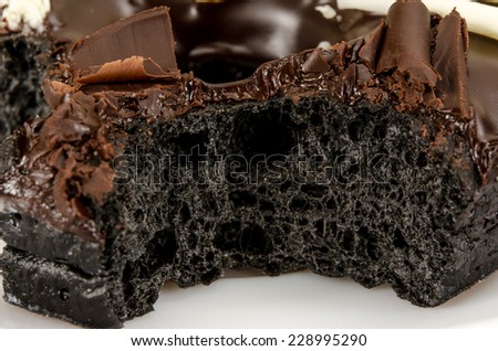 Close up of Chocolate donut with bite taken out in white dish on brown sack background