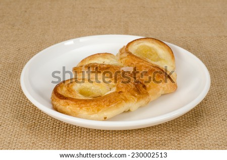 Image of  pineapple danish pastry in white dish on brown sack background