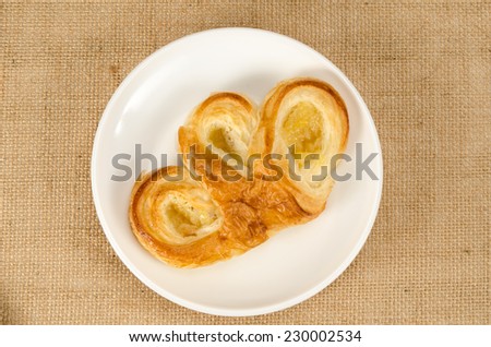 Image of  pineapple danish pastry in white dish on brown sack background