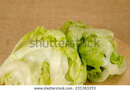 Image of green iceberg lettuce on wood cutting board on brown sack background