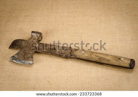 Image of ancient metal axe on brown sack background