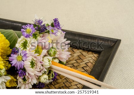Image of flowers in banana leaf cone with incense and candle on sack fabric background