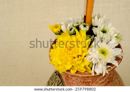 Image of flowers in clay vase with incense and candle on sack fabric background