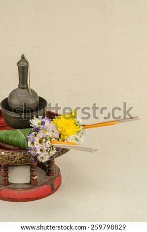 Image of flowers in banana leaf cone with incense and candle on sack fabric background