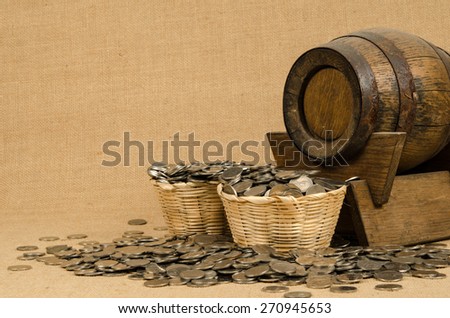 Stack of coins with wooden barrel on brown sack background