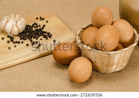 Wet eggs in bamboo woven bucket on brown sack background