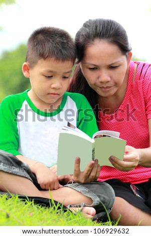 Mother and son reading a book, relaxing time in the garden