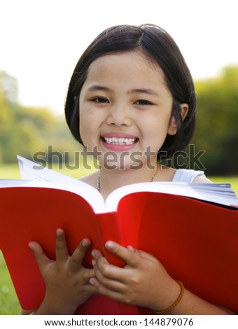 Little girl opened the book in the park