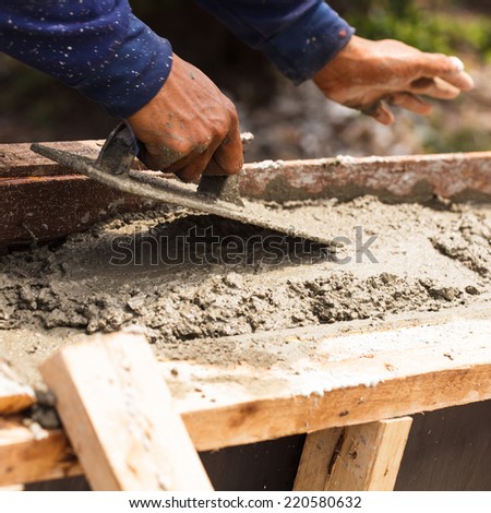 Construction workers at a construction site,  hand using smooth the cement screed with trowel