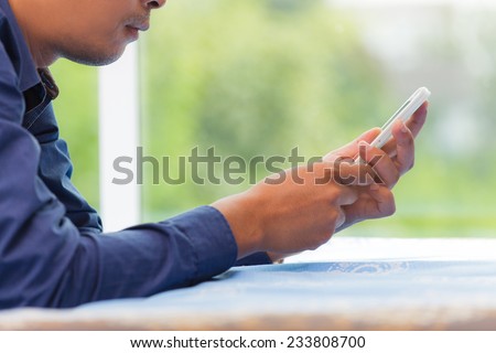 Close-up portrait of a relaxed man using the phone on the bed at home