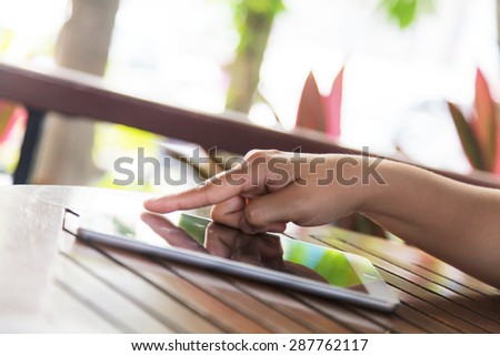 Cropped view of women using a digital tablet at outdoor coffee shop