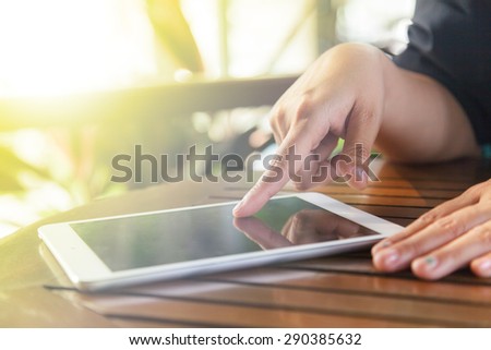 Cropped view of women using a digital tablet at outdoor coffee shop