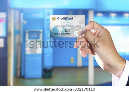 Hand holding credit card with ATM machines