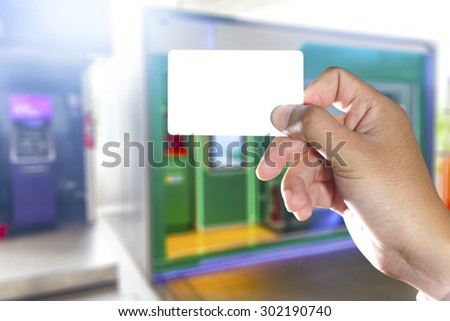 Hand holding blank white card with ATM machines