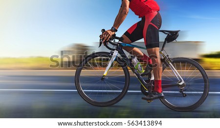 Man on a bicycle on a road with motion blur of truck on highway at morning light