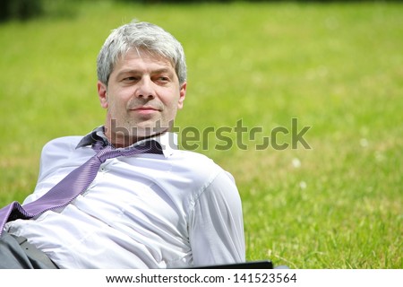 A young self-confident businessman lying in the nature and looking to the distance.../I love my job