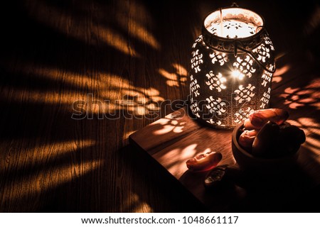 Dates in wooden bowl and Arabian lantern on wooden floor. Eid lamp or lantern for Ramadan and other Islamic Muslim holidays, with copy space for text